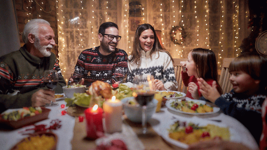 Cheerful multi-generation family communicating while enjoying in Christmas meal at dining table.