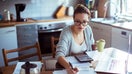 Close up of a young woman doing her bills in the kitchen