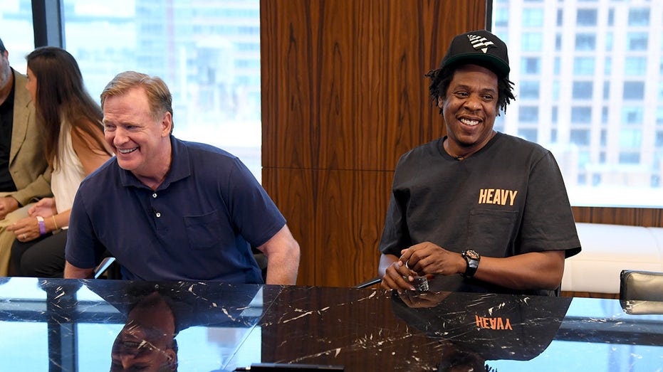 Jay-Z laughs next to NFL commissioner Roger Goodell